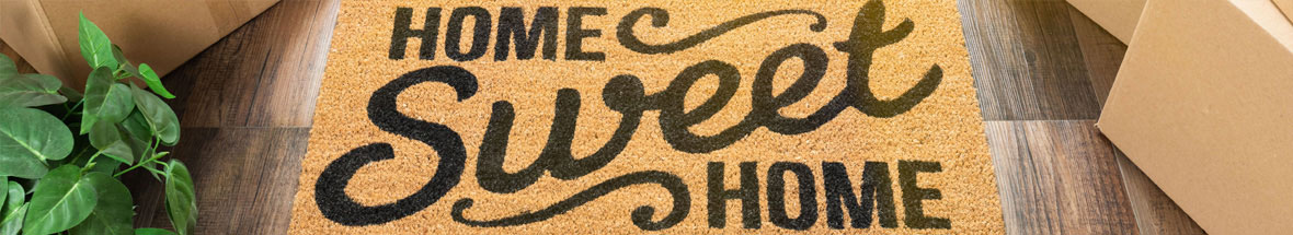 doormat with 'Home Sweet Home' surrounded by packing boxes