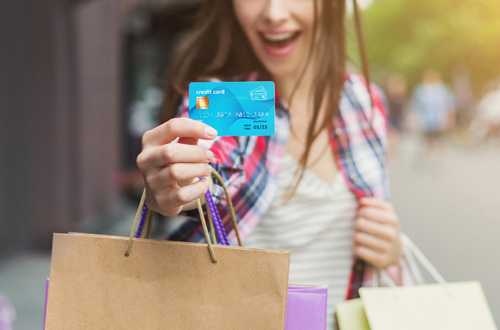 smiling woman holding credit cards and shopping packages